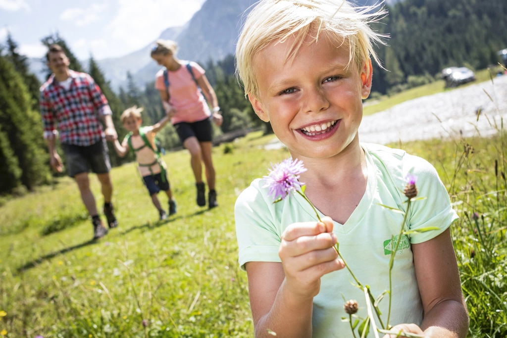 Familie mit zwei Kindern wandert über Almen im Familienurlaub in Österreich