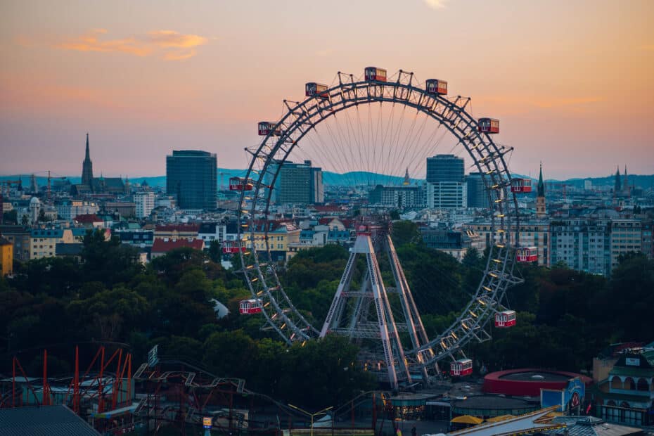 Das Riesenrad in Wien in der Abendsonne, im Hintergrund die Stadt und Hotels in Wien.
