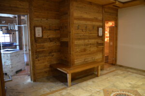 Saunastube mit Holzverkleidung an der Wand und Holzbank vor der Sauna