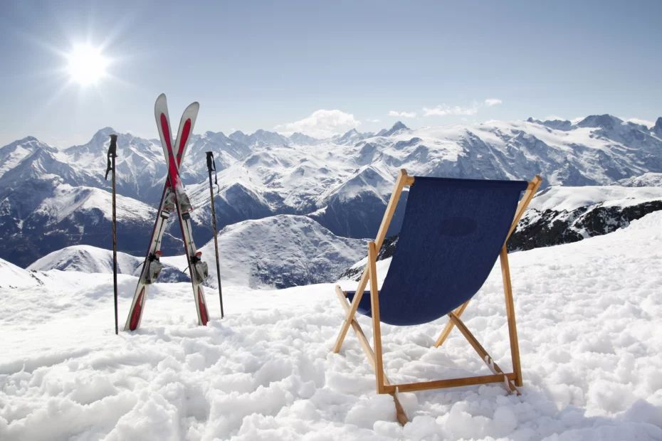 Liegestuhl und Skier im Winterurlaub auf einer sonnigen Piste